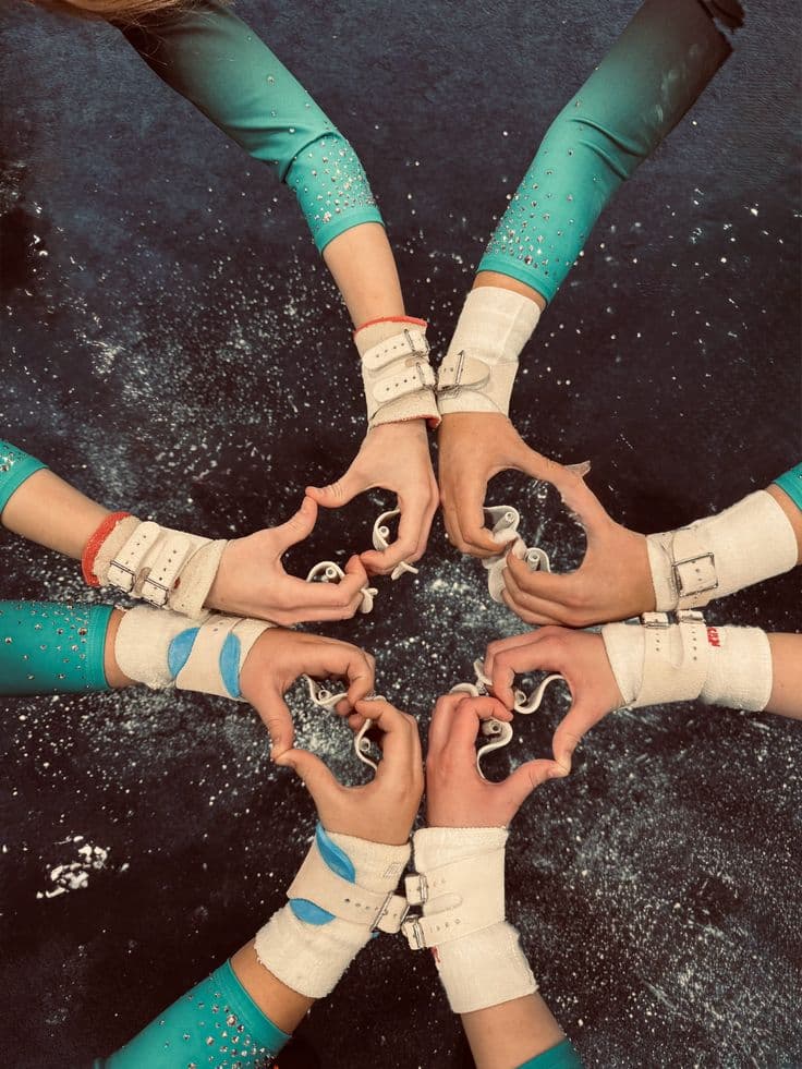 Spartans Academy gymnasts in teal competition leotards joining hands in a star over the chalked training floor